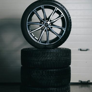 Car tires stacked with an alloy wheel on top in a garage setting. Perfect for automotive themes.
