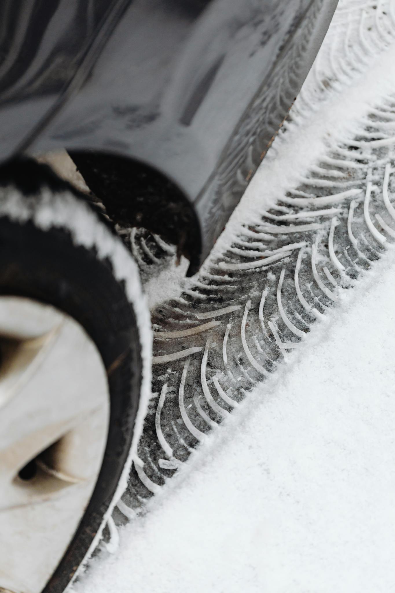 Detailed view of car tire and tracks on snowy ground highlighting winter conditions.