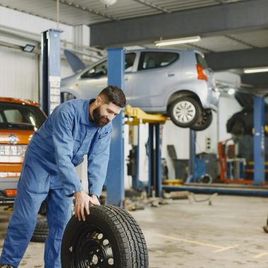 Mechanic handling a tire in a busy automotive repair workshop.